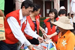 Các tình nguyện viên Hội Chữ Thập đỏ trao hàng cứu trợ cho người dân vùng lũ lụt. (Ảnh: Hồ Cầu/TTXVN)