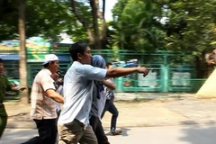 Đối tượng bắt cóc em học sinh (áo chùm đầu) được đưa về cơ quan công an. (Ảnh: Hoàng Anh Tuấn/Vietnam+) 