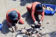 Công nhân Công ty Đoàn Ánh Dương tiến hành khai quật cổ vật từ con tàu bị đắm ở Quảng Ngãi. (Ảnh: Thanh Long/TTXVN)