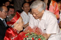 Tổng Bí thư Nguyễn Phú Trọng thăm hỏi, tặng hoa chúc mừng nhà văn Học Phi. (Ảnh: Trí Dũng/TTXVN)