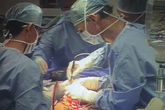 Phó Giáo sư McKay McKinnon (phải) trực tiếp phẫu thuật cắt bỏ khối u cho anh Hải. (Ảnh: Phương Vy/TTXVN)