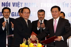 Tổng Giám đốc Thông tấn xã Việt Nam Nguyễn Đức Lợi và Bộ trưởng Bộ Tài chính Vương Đình Huệ bắt tay chúc mứng sau lễ ký. (Ảnh: Phạm Hậu/TTXVN)