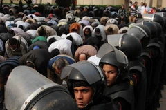 Lực lượng an ninh Ai Cập canh gác bên những người biểu tình ủng hộ Tổng thống Morsi ở bên ngoài trụ sở Tòa án Hiến pháp Tối cao Ai Cập, tháng 12/2012. (Nguồn: Xinhua)