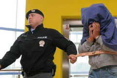 Một cảnh sát Séc dẫn một nghi can sản xuất rượu lậu tới tòa án ở Zlin, Séc. (Nguồn: AP)