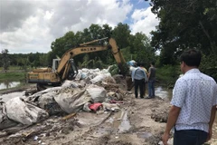 Lực lượng chức năng bắt quả tang hành vi chôn rác thải y tế không qua xử lý. (Ảnh: Thanh Tân/TTXVN)