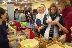 Khách nước ngoài thăm và mua sản phẩm thủ công mỹ nghệ tại Gian hàng của Việt Nam. (Ảnh: Duy Trinh/Vietnam+)