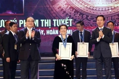 Trưởng Ban Tuyên giáo Trung ương Võ Văn Thưởng và Bí thư Thành ủy Hà Nội Hoàng Trung Hải vinh danh Công dân Thủ đô ưu tú năm 2018 đối với nghệ nhân ưu tú Phạm Thị Tuyết, Chủ nhà hàng Ánh Tuyết (25 Mã Mây, Hoàn Kiếm). (Ảnh: Văn Điệp/TTXVN)