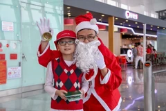 Hành khách nhí chụp hình và nhận món quà từ Ông già Noel của Cảng hàng không Nội Bài. (Ảnh: Dương Phạm/Vietnam+)