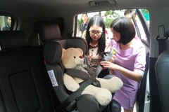 Phụ huynh thực hành cài dây an toàn ở ghế ngồi sau. (Ảnh: Việt Hùng/Vietnam+)