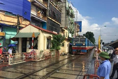 Công nhân kéo dàn gác chắn đường ngang để những chuyến tàu hỏa chạy qua an toàn. (Ảnh: Việt Hùng/Vietnam+)