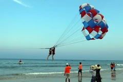 Khách du lịch tham gia trò chơi canô kéo dù tại biển Phạm Văn Đồng (Đà Nẵng). (Ảnh: Trần Lê Lâm/TTXVN)