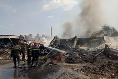 Lính cứu hỏa phun nước làm nguội hiện trường vụ cháy. (Ảnh: Thành Chung/TTXVN)