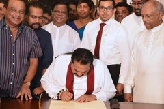 Thủ tướng Sri Lanka Mahinda Rajapakse (giữa) ký đơn từ chức tại Colombo ngày 15/12/2018. (Ảnh: AFP/TTXVN)