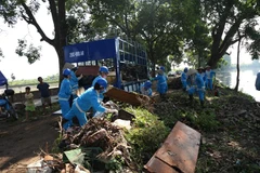 Công nhân vệ sinh môi trường đô thị Gia Lâm thực hiện thu gom rác thải bên bờ sông Cầu Bây. (Ảnh Mạnh Khánh/TTXVN)