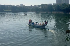 Công ty TNHH MTV Thoát nước Hà Nội đang xử lý chế phẩm tại hồ Nghĩa Tân. (Ảnh: Mạnh Khánh/TTXVN)