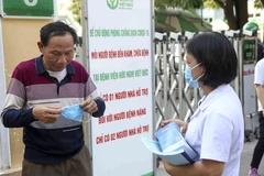 Nhân viên y tế phát khẩu trang cho một số người dân chưa tuân thủ việc đeo khẩu trang phòng, chống dịch bệnh. (Ảnh: Tuấn Đức/TTXVN)