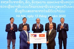 Thứ trưởng Bộ Ngoại giao Nguyễn Quốc Dũng (bên phải) trao tượng trưng 1.000 tấn gạo cho đại diện Đại sứ quán Lào tại Việt Nam trước sự chứng kiến của Thủ tướng Nguyễn Xuân Phúc. (Ảnh: Thống Nhất/TTXVN)