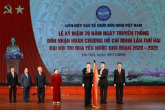 Phó Thủ tướng, Bộ trưởng Bộ Ngoại giao Phạm Bình Minh gắn Huân chương Hồ Chí Minh lên lá Cờ truyền thống của Liên hiệp các tổ chức hữu nghị Việt Nam. (Ảnh: Văn Điệp/TTXVN)