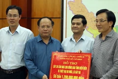 Ông Tất Thành Cang (thứ 2 từ trái sang) trao tặng bảng tượng trưng số tiền hỗ trợ cho đồng bào bị mưa lũ. (Ảnh: Phan Tuấn Anh/TTXVN)