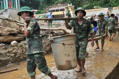 Các chiến sỹ Sư đoàn 316 - Quân khu 2 tham gia dọn dẹp bùn đất sau lũ. (Ảnh: Đinh Hữu Dư/TTXVN)