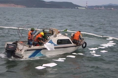 Giấy thấm hút dầu được thả trong khu vực để hạn chế ô nhiễm môi trường. (Ảnh: Khiếu Tư/TTXVN)