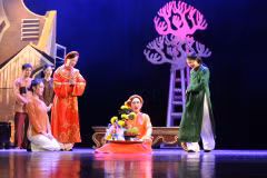 Cụ Thông (Nghệ sỹ nhân dân Lê Khanh, áo đỏ) và con dâu (diễn viên Khuất Quỳnh Hoa áo xanh) mải mê dốc tiền cho những hoạt động mê tín dị đoạn. (Ảnh: Minh Anh/Vietnam+)
