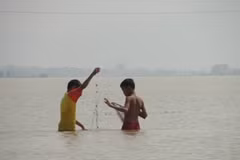 Trẻ thơ mưu sinh giữa lũ. (Ảnh: Sơn Bách/Vietnam+)