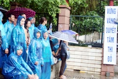 Dù trời mưa to, nhiều phụ huynh "bám trụ" tại cổng trường đợi các sĩ tử. (Ảnh PV/Vietnam+) 