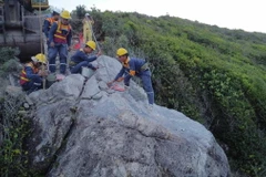 Lực lượng chức năng tiến hành khoan khối đá nằm trên đỉnh đèo Cù Hin. (Ảnh: Đặng Tuấn/TTXVN)
