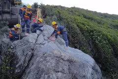 Lực lượng chức năng tiến hành khoan khối đá nằm trên đỉnh đèo Cù Hin. (Ảnh: Đặng Tuấn/TTXVN)
