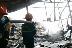 Các chiến sỹ cảnh sát Phòng cháy chữa cháy đang tích cực dập tắt khu vực còn cháy âm ỉ bên trong. (Ảnh: Quốc Dũng/- TTXVN)