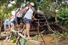 Du khách quốc tế trải nghiệm đi cầu khỉ tại cù lao Thới Sơn. (Ảnh: An Hiếu/TTXVN)