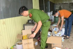 Công an kiểm tra kho chứa các vật dụng, máy móc làm giả tem nhãn của nhóm đối tượng. (Ảnh: TTXVN phát)
