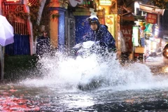 Người dân đi lại khó khăn khi trời mưa to tại phố Bùi Sương Trạch, quận Thanh Xuân. (Ảnh: Tuấn Anh/TTXVN)