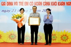 Phó Chủ tịch UBND Thành phố Hồ Chí Minh Trần Thị Diệu Thúy trao quyết định công nhận quận Phú Nhuận hoàn thành mục tiêu không còn hộ nghèo đa chiều thành phố giai đoạn 2021-2025. (Ảnh: Thanh Vũ/TTXVN)