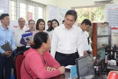 Phó Chủ tịch UBND thành phố Hà Nội Hà Minh Hải trao đổi với người dân làm thủ tục hành chính tại UBND phường Quảng An, quận Tây Hồ. (Ảnh: Nguyễn Thắng/TTXVN)