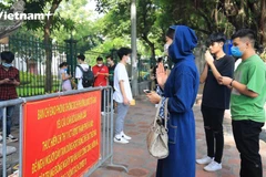 Sỹ tử cùng phụ huynh khấn vái tại cửa Văn Miếu-Quốc Tử Giám (Ảnh: Hoàng Đạt/Vietnam+)