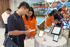 Độc giả trải nghiệm một số thiết bị điện tử chuyên dùng để đọc sách. (Ảnh: Minh Thu/Vietnam+)