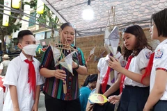 Bà Nguyễn Thị Tuyến ở Hoài Đức hướng dẫn các em thiếu nhi làm đèn ông sao. (Ảnh: Minh Thu/Vietnam+)