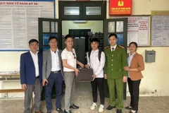 Em Nguyễn Bá Biền (thứ 3 từ phải) trả lại tiền cho người đánh rơi. (Ảnh: TTXVN phát)