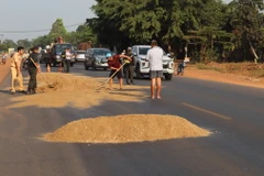 Trạm Cảnh sát Giao thông Đồng Phú và các lực lượng khắc phục sự cố trơn trượt trên Quốc lộ 14. (Ảnh: Đậu Tất Thành/TTXVN)