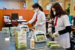 Khách hàng giao dịch tại ngân hàng. (Ảnh: Vietnam+)