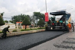 Các đơn vị thi công thảm lại nhựa mặt đường. (Ảnh: Dương Chí Tưởng/TTXVN)