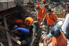 Lực lượng cứu hộ Indonesia tìm kiếm các nạn nhân còn mắc kẹt trong đống đổ nát sau trận động đất tại tỉnh Aceh ngày 7/12. (Ảnh: AFP/TTXVN)