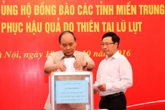 Thủ tướng Nguyễn Xuân Phúc và Phó Thủ tướng, Bộ trưởng Ngoại giao Phạm Bình Minh quyên góp ủng hộ đồng bào các tỉnh miền Trung khắc phục hậu quả do thiên tai lũ lụt. (Ảnh: Thống Nhất/TTXVN)