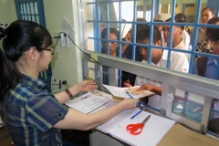 Nhân viên điểm cấp đổi giấy phép lái xe giao giấy phép lái xe cho các chủ phương tiện xin cấp, đổi. (Ảnh: Hoàng Hải/TTXVN)