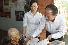 Phó Chủ tịch Ủy ban Mặt trận Tổ quốc Thành phố Hồ Chí Minh Trần Tấn Hùng trao quà cho Mẹ Việt Nam Anh hùng Bùi Thị Diệp. (Ảnh: Hoàng Hải/TTXVN)