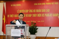 Bộ trưởng Bộ Công Thương Trần Tuấn Anh quyên góp ủng hộ nhân dân Lào. (Ảnh: Trần Việt/TTXVN)