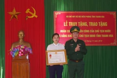 Vợ thiếu tá Vi Văn Nhất đón nhận Huân chương Chiến công hạng Nhất. (Ảnh: Trịnh Duy Hưng- TTXVN)