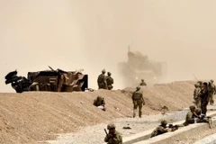 Binh sỹ Mỹ gác tại hiện trường, bên chiếc xe hộ tống bị phá hủy sau vụ tấn công ở Kandahar ngày 2/8. (Nguồn: EPA/TTXVN)